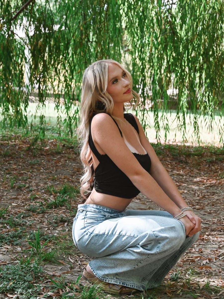 Senior crouching by a willow-lined creek
